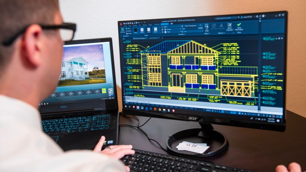 A monitor showing a coloured two-dimensional building elevation, hands at the keyboard below