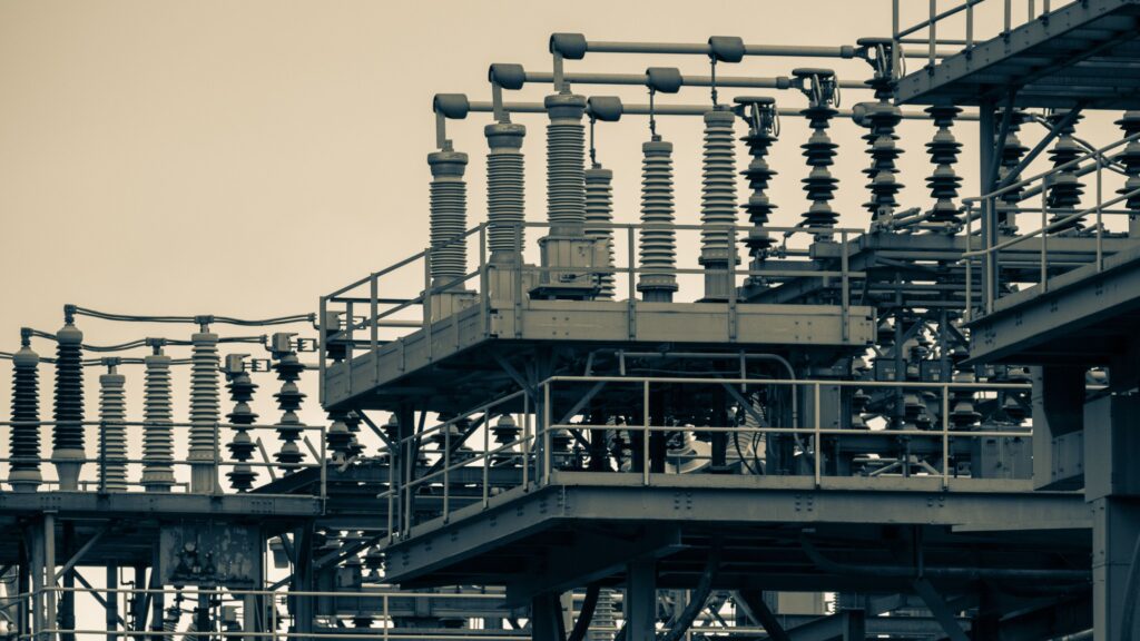Steel gantries, insulators and busbars inside an outdoor electrical substation