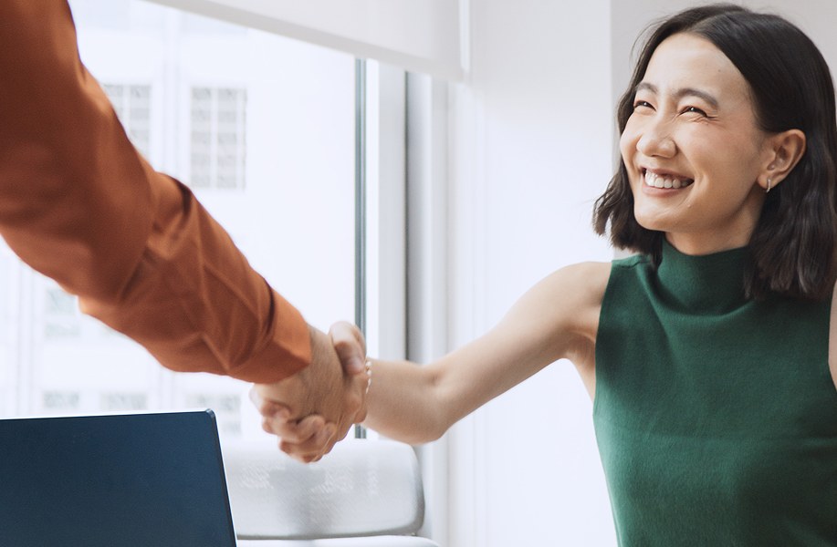 Two people shaking hands beside an office window