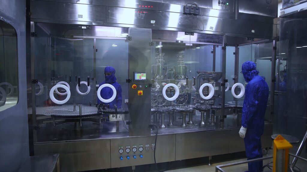 A row of stainless steel isolators with glove ports along a sterile production line