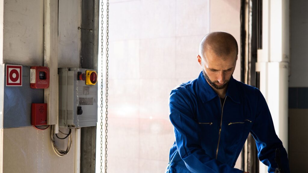 A technician in blue overalls at work in a building plant room