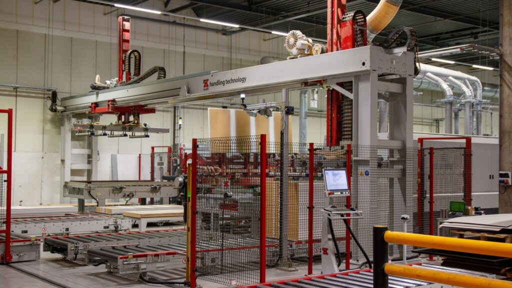 A gantry robot on rails above a conveyor in a bright, empty production hall