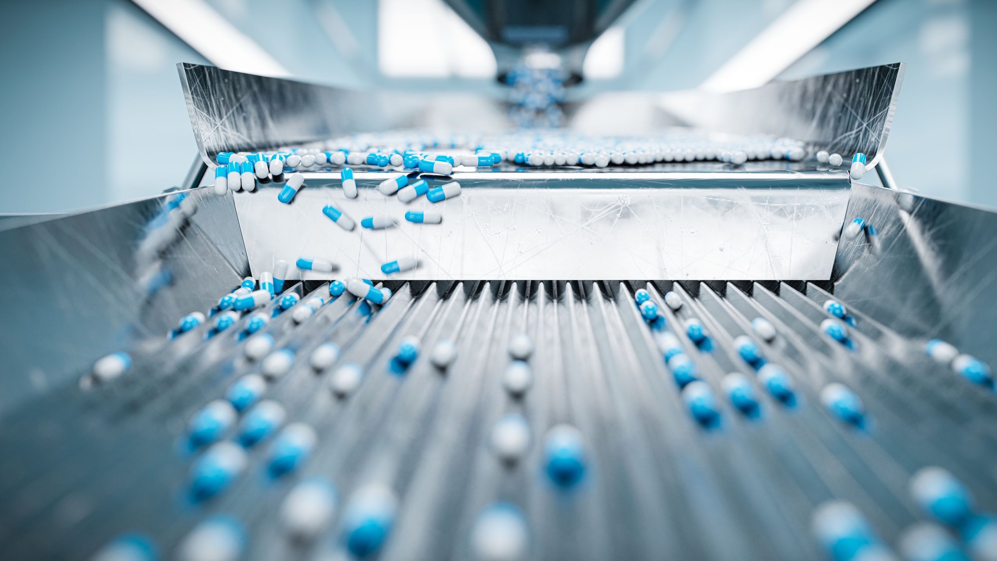 Blue and white capsules moving along a pharmaceutical production line