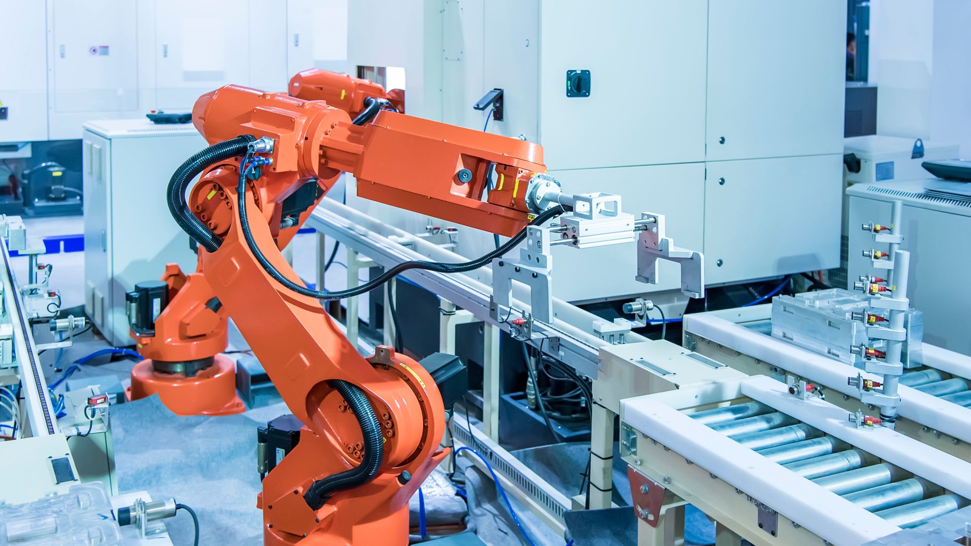 An orange robotic arm working over a conveyor in a clean production cell