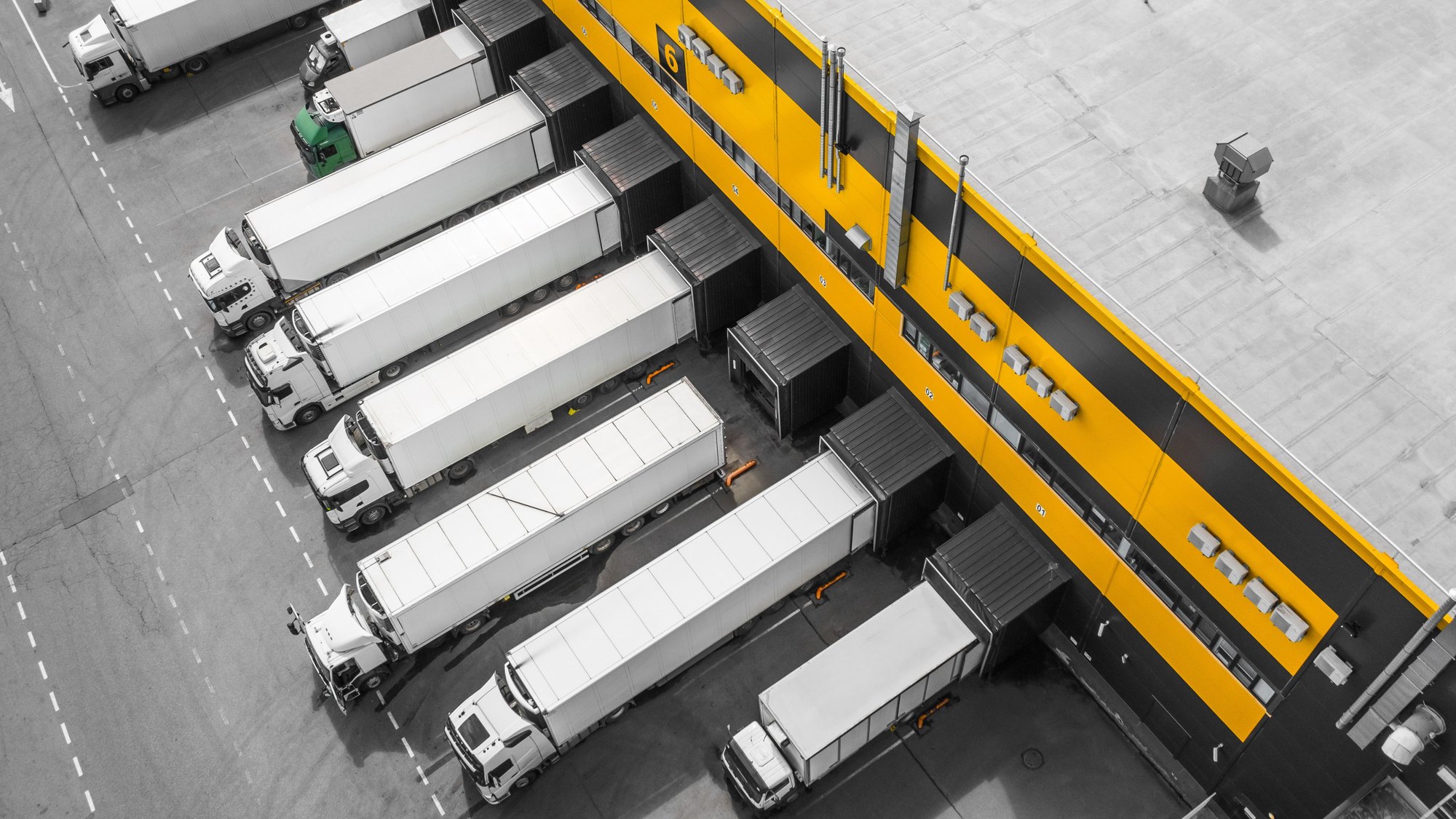 An overhead view of articulated lorries backed into a row of loading bays