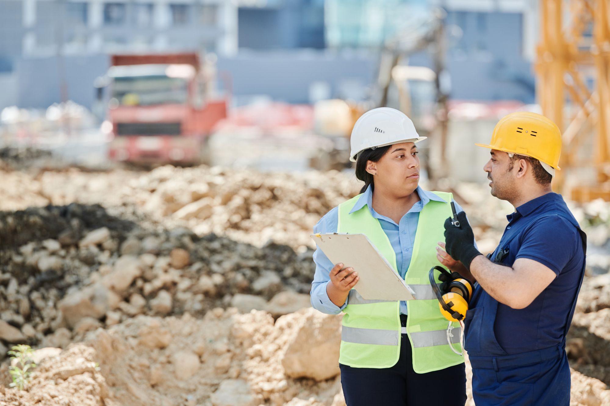 A site supervisor with a clipboard talking with a technician on a construction site