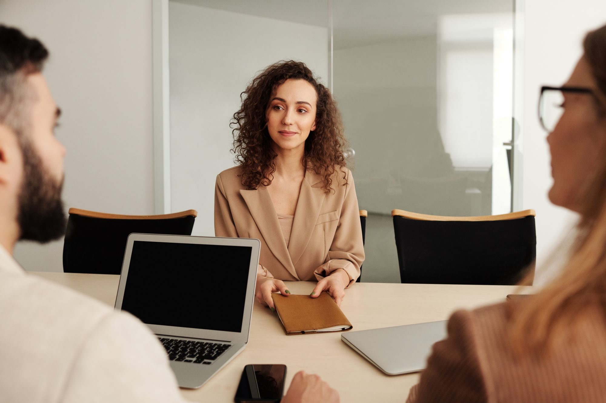 A candidate in a beige blazer across the table from two interviewers