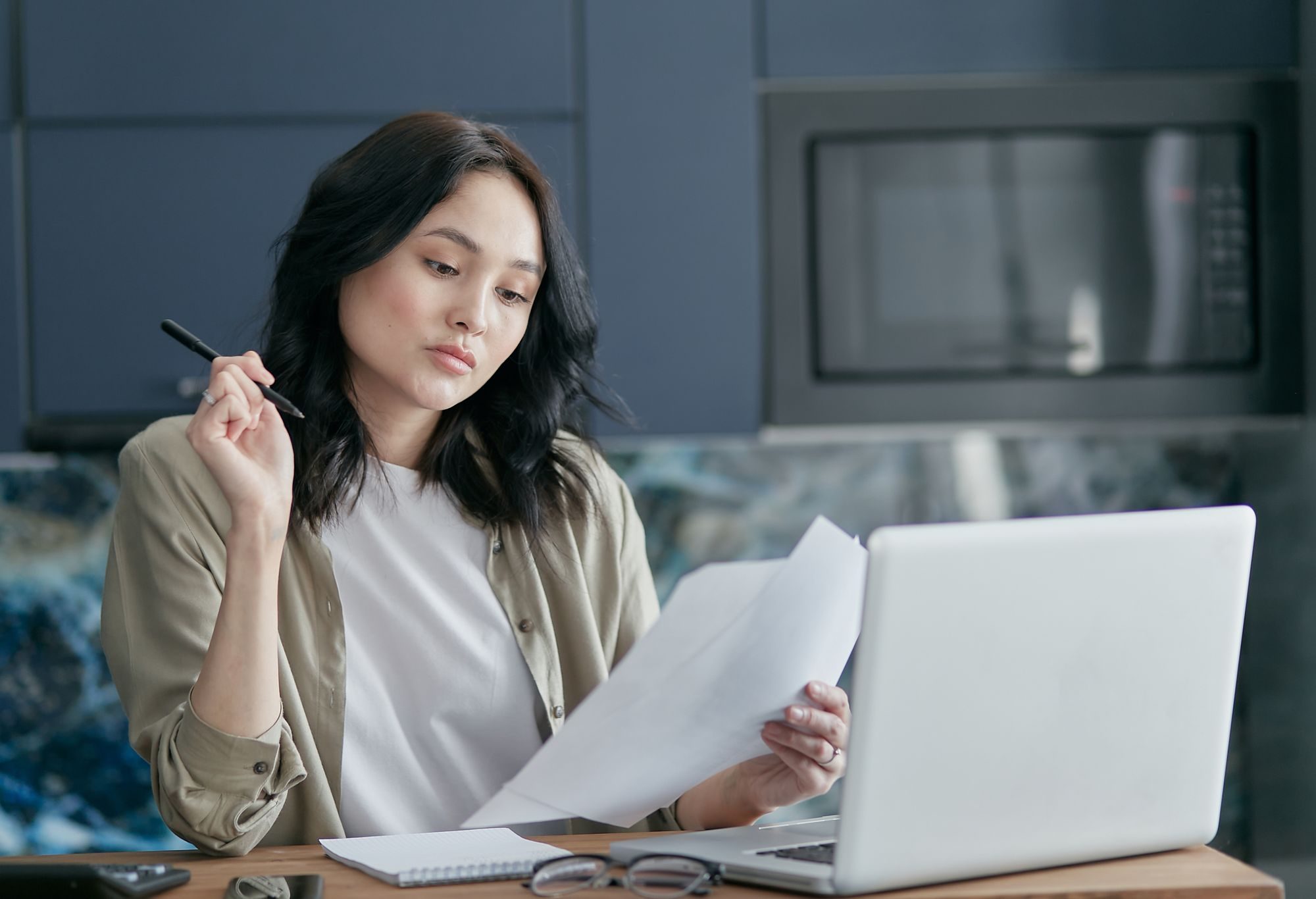 A professional at her desk reading through a document with a pen in hand