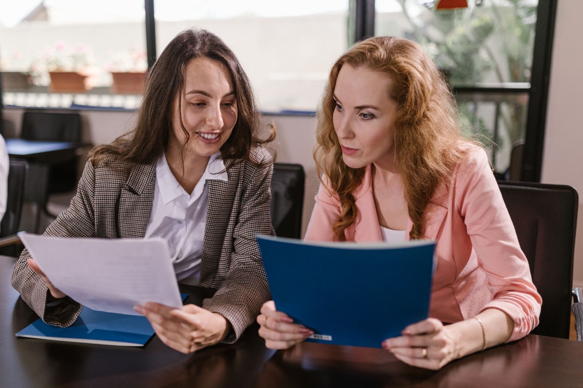 Two colleagues at a table reviewing a document and a folder together